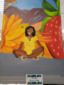 original painting of a girl sitting with sunflower and strawberry in background