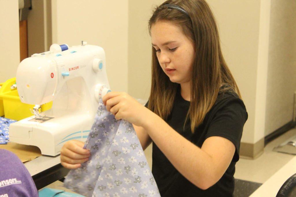 4-H youth participating in sewing camp and looking at project