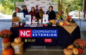 6 people standing behind a table that says NC Cooperative Extension