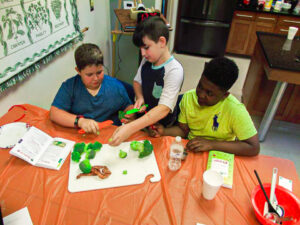 Three Children Prepping food for a meal during Summer Cooking Campt