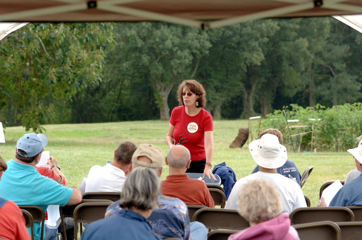 Woman in Red Shirt Teaching People about Agriculture