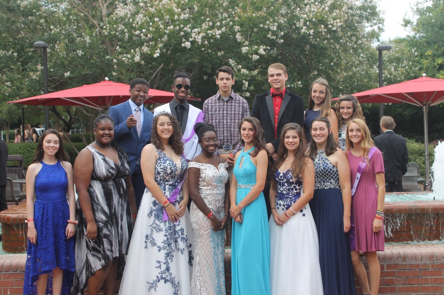 A group of well dressed youths posing for a photo in front of a fountain.